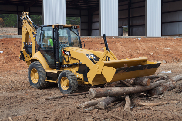 A CAT 416F Backhoe Loader moving logs for a construction operation.